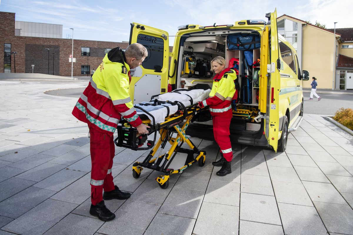 Noen få menn i røde dresser som dytter en gul lastebil