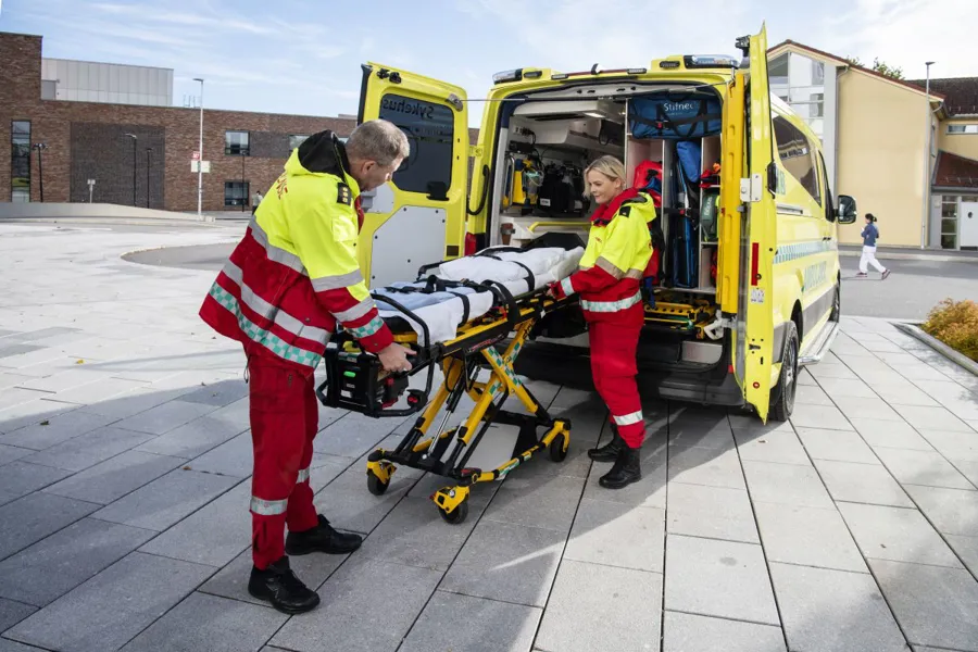Noen få menn i røde dresser som dytter en gul lastebil