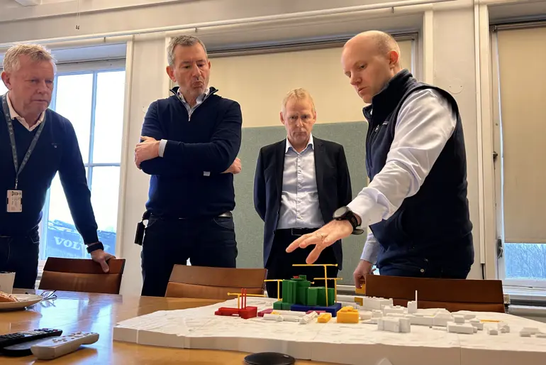 En gruppe menn som står rundt et bord med et modelltog