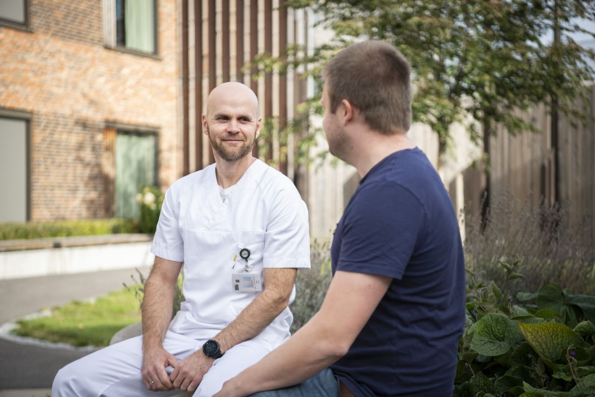 En mann som sitter på fanget til en mann utenfor