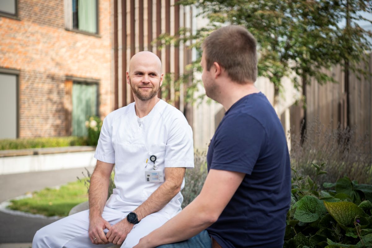 En mann som sitter på fanget til en mann utenfor