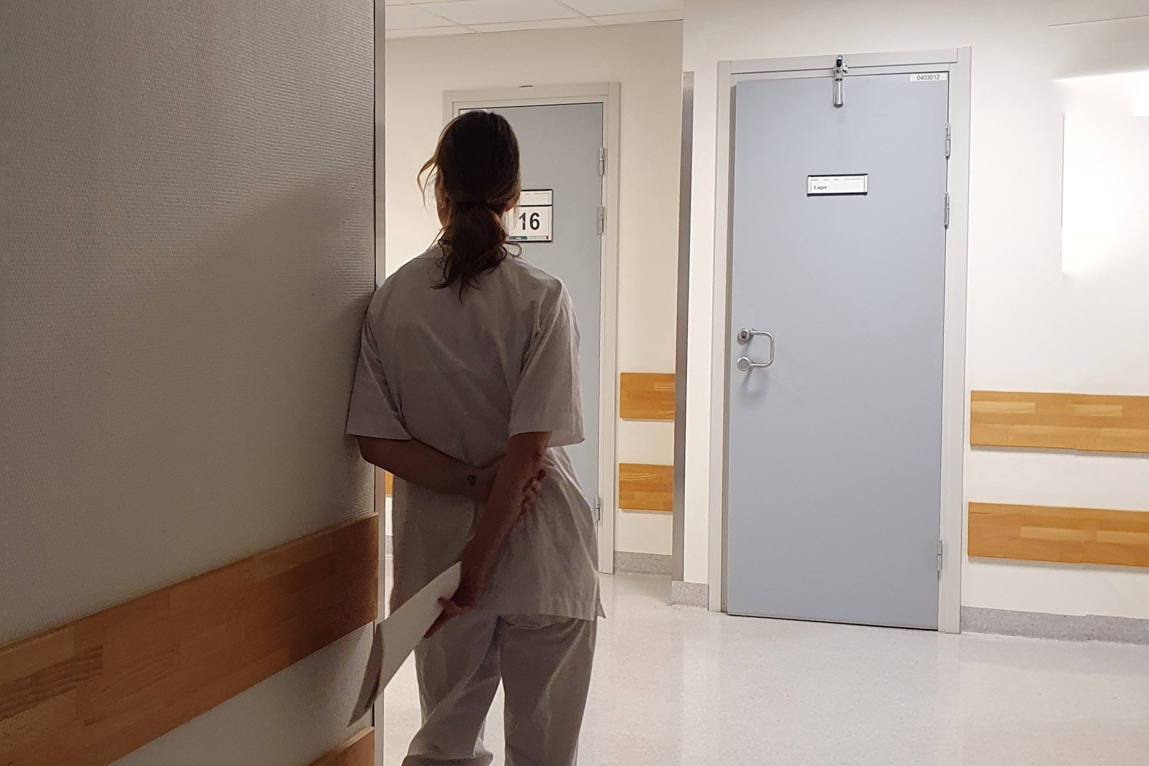 Sykepleier som står i en korridor med ryggen til