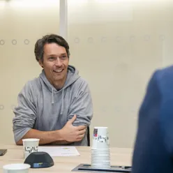 Smilende mann ved et møtebord med flere