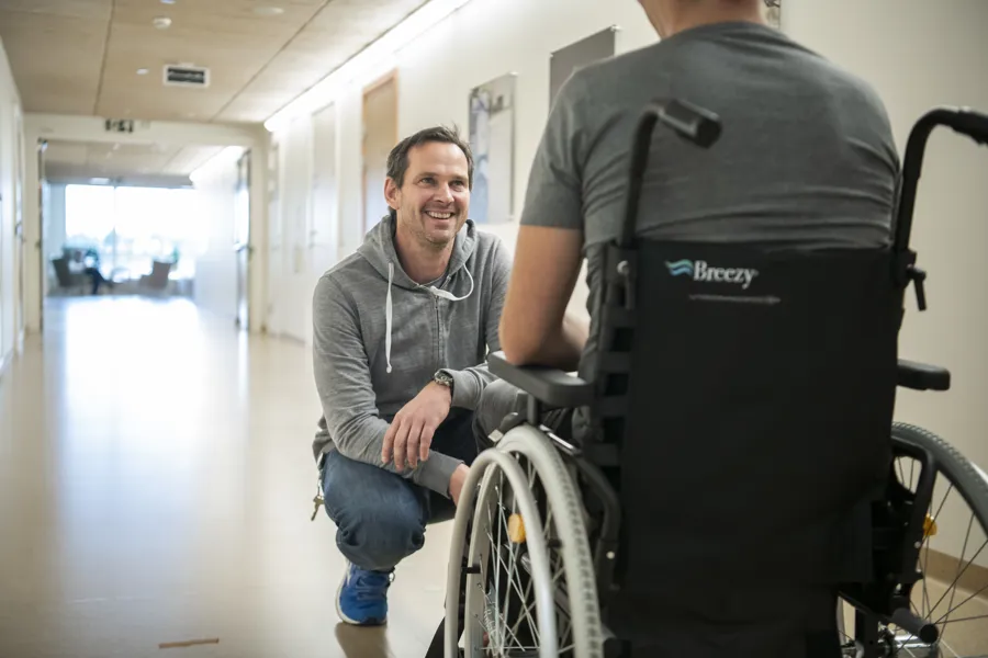 Pleier snakker med pasient i rullestol